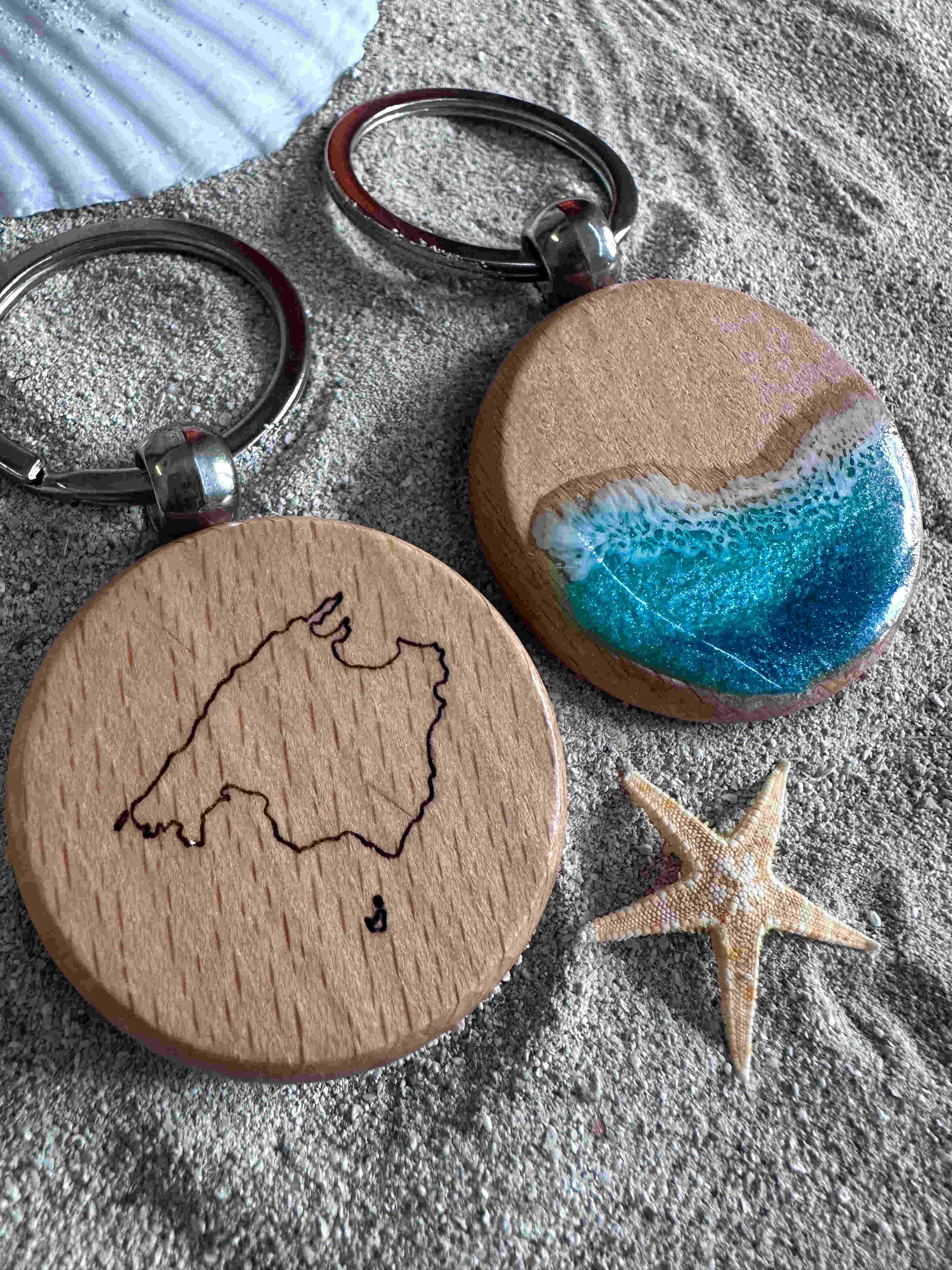 Keychain on beach sand next to seashells