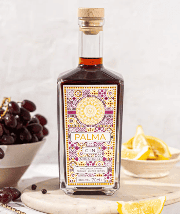 Limited edition bottle of gin next to a bowl with citrus fruits and another with grapes