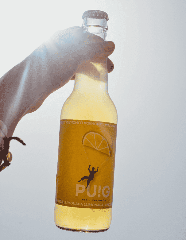 Mano sujetando botella de refresco con rayos de sol de fondo