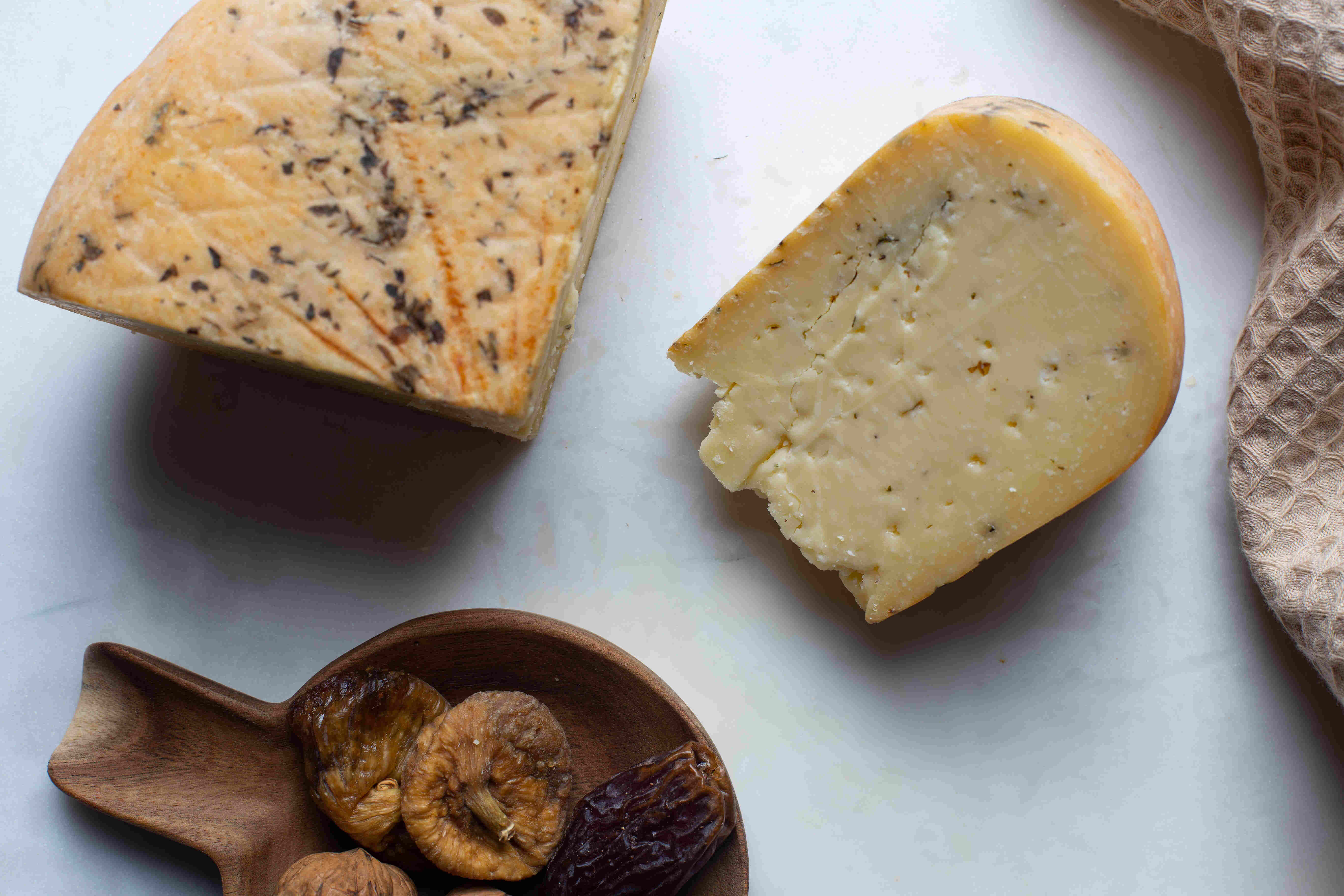 Image of a cut artisan semi-cured cheese with fine herbs.