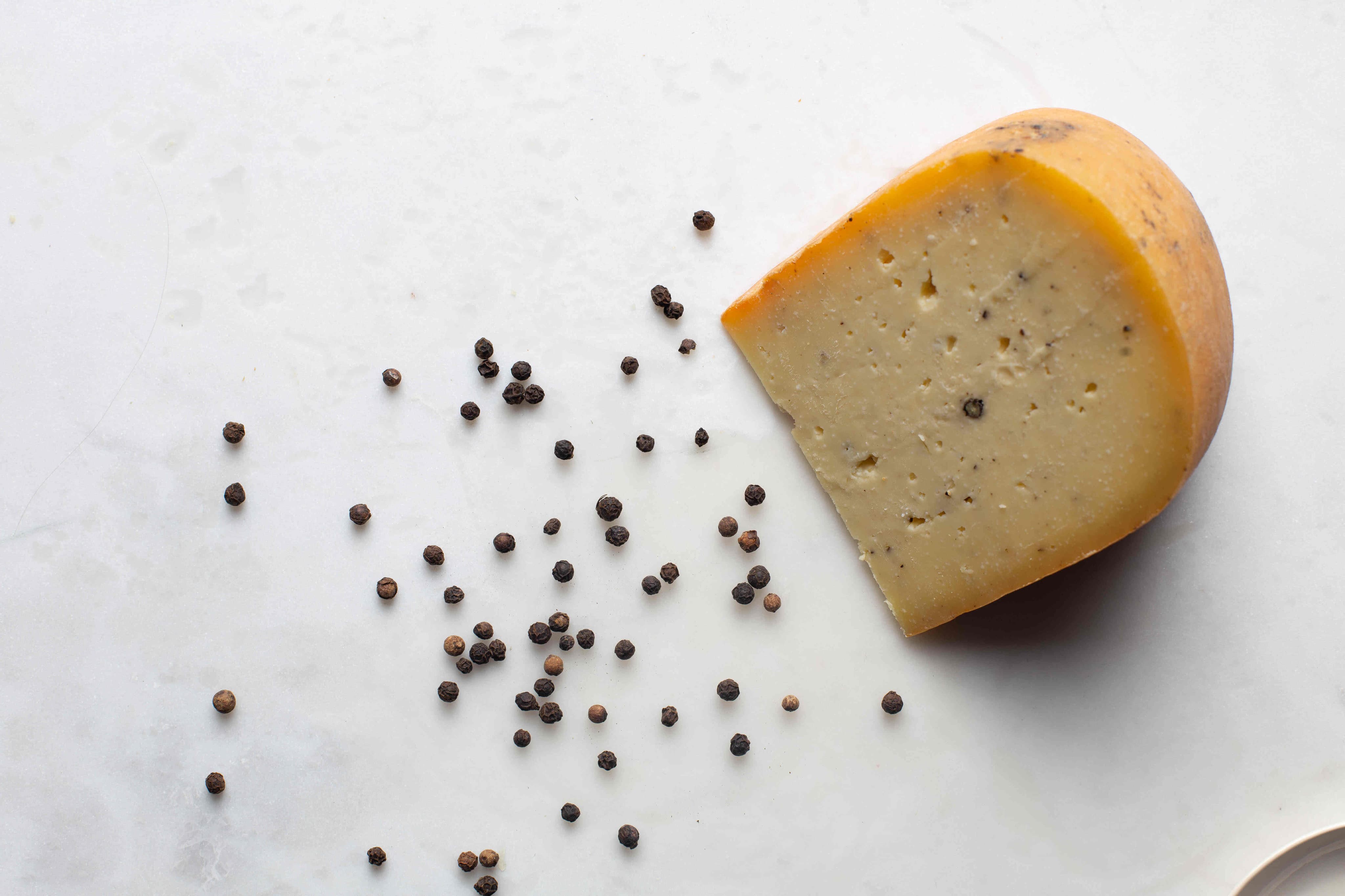 Image of a semi-cured cheese with pepper, artisan, cut.